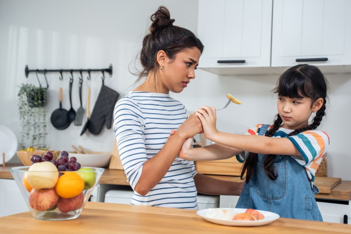 child stopping her mother from feeding her
